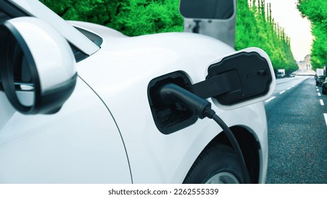 Progressive green city ESG green trees background with electric vehicle, EV car recharge energy at the charging point to increase environmental awareness with renewable energy powered transportation. - Shutterstock ID 2262555339
