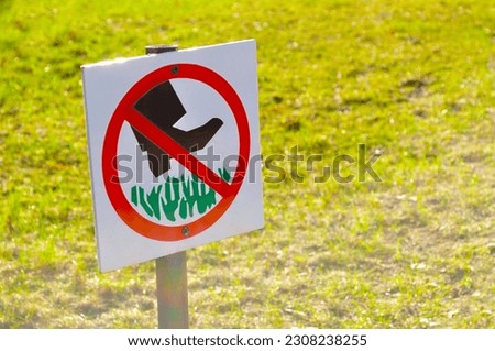 The prohibitive sign on the label Do not walk the lawn - closeup against tha lawn in sunlight