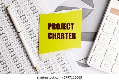 Project charter concept with sticky note, calculator, financial documents and pen representing project planning, scope definition,.