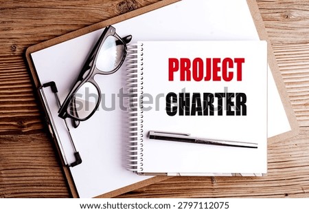 Project charter document on office desk with notebook, pen and eyeglasses, representing project management planning . 