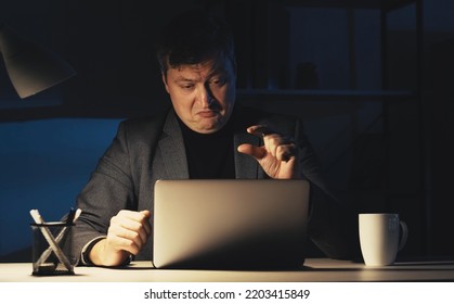 Project Fail. Criticizing Man. Online Meeting. Dissatisfied Business Guy Showing Finger Small Gesture Talking Laptop Sitting Desk Dark Room Interior.