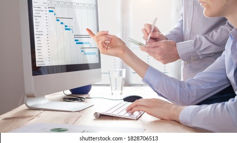 Project management team updating planning schedule with Gantt chart on computer at the office to communicate on task progress and plan the next deliverables. Program manager and assistant discussing - Shutterstock ID 1828706513