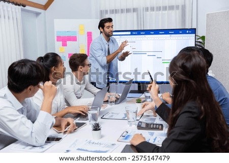 Project manager communicate and collaborate with team using project management software display on monitor, tracking progress of project task and making schedule plan at meeting table. Prudent
