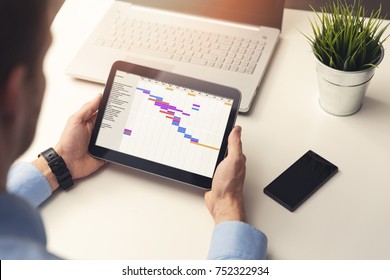 Project Manager Looking At Gantt Chart On Digital Tablet In Office