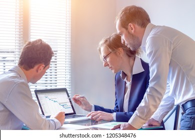 Project Manager Meeting With Team For Decision On Planning Milestones And Deliverables, Gantt Chart Schedule On Computer Screen, 3 People In Office