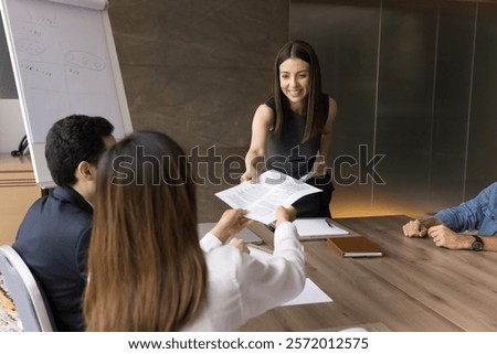 Project manager offering plan, management strategy to diverse team, share financial reports, gives papers, legal document or contract text for learning before signing during group at corporate meeting