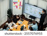 Project manager planning schedules for business task at meeting room, Gantt chart software show on TV screen. Multi ethnic diversity business people and modern business project management. Meticulous