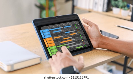 Project manager using a tablet to track multiple projects, tasks, timelines, and deadlines with a digital Gantt chart, supporting efficient workflow planning,