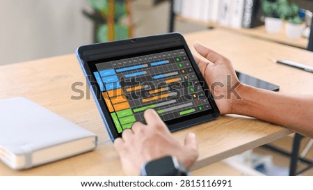 Project manager using a tablet to track multiple projects, tasks, timelines, and deadlines with a digital Gantt chart, supporting efficient workflow planning,