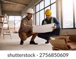 Project manager and worker cooperating while going through rebuilding plans at construction site. 