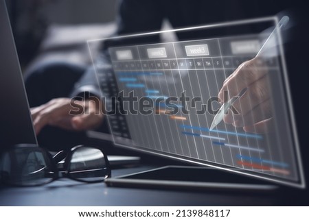 Project manager working and update tasks with milestones progress planning. Businessman using laptop computer and digital tablet with Gantt chart scheduling virtual diagram, project management concept