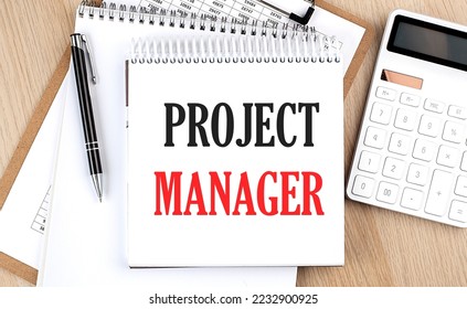 PROJECT MANAGER is written in white notepad near calculator, clipboard and pen. Business concept - Shutterstock ID 2232900925
