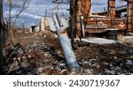 A projectile from a multiple launch rocket system has stuck into the ground, sticking out of the ground in the yard of a destroyed house in a Ukrainian village. Consequences of the shelling of a