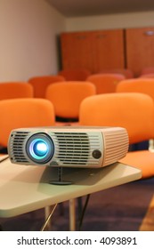 Projector on table ready for presentation with chairs on background