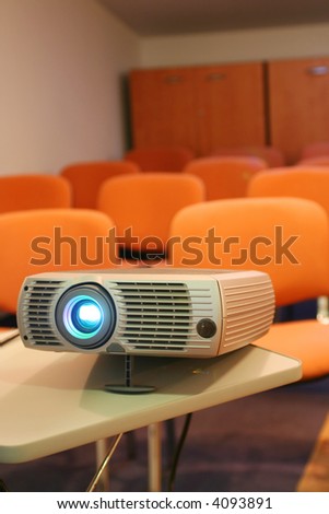Projector on table ready for presentation with chairs on background