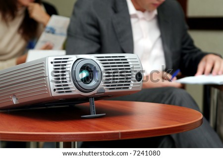Projector on table with two person behind (horizontal)