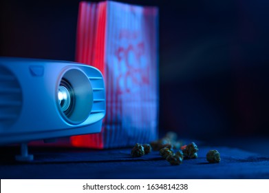 Projector For Watching Movies For Home, Or A Movie Theater With Popcorn On A Dark Background For Design. Concept. Viewing A Movie At Home In Comfort Or A Movie Theater.