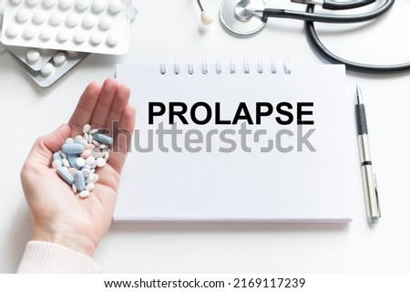 PROLAPSE text on notepad on a light table next to hand vrcha with tablets and stethoscope on the table, medical concept