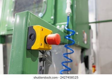 Prominent red emergency stop button mounted on a piece of green industrial equipment, poised to halt operations immediately for safety reasons during manufacturing or assembly processes - Powered by Shutterstock