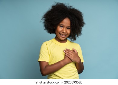 I Promise To Be Honest. Portrait Of Happy Responsible Little Girl Holding Her Hand At Her Heart. Child Swearing To Tell Truth. Studio Shot Isolated On Blue Background 