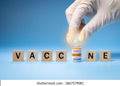 Promising Covid-19 Vaccine concept. Hand of a researcher take a 2019-nCov vaccine vial with wooden alphabet letters "VACCINE". Candidates, Authorized, Volunteers, Global trial, Hope, Successful.