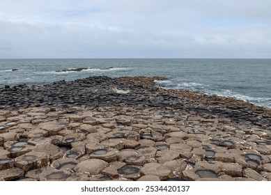 A promontory of hexagonal basalt columns extends into the Atlantic Ocean at Giant Causeway in Northern Ireland, with waves crashing on the rugged formation