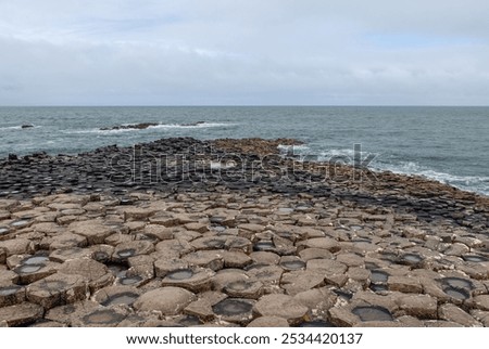 A promontory of hexagonal basalt columns extends into the Atlantic Ocean at Giant Causeway in Northern Ireland, with waves crashing on the rugged formation