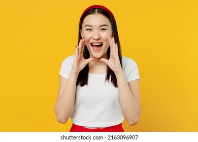 Promoter funny charming young woman of Asian ethnicity 20s years old wears white t-shirt scream hot news about sales discount with hands near mouth isolated on plain yellow background studio portrait