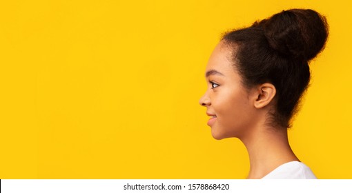 Promotion Concept. Side View Portrait Of Smiling Black Girl Looking At Copy Space Over Yellow Background. Panorama