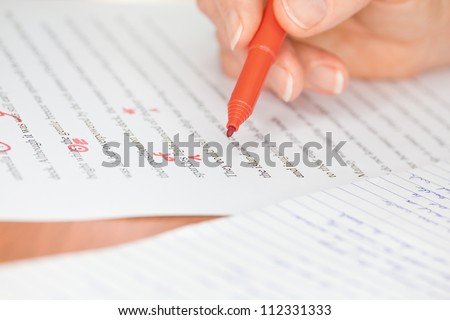 Proofreader with red pen checks a transcribed page
