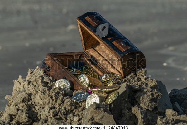 prop treasure chest open on the beach with fake\
coins and jems