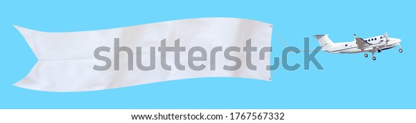 Propeller aircraft with a\
long white advertising banner made of fabric. Isolated on a blue\
background