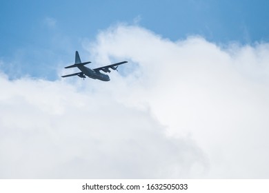 A propeller airplane in the sky flying away from us overhead