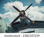 Propeller and wing of an old aircraft in front of the cloudy sky. Close-up view of teal green 1950s gull-winged vintage aircraft. Vintage piece of aviation in a open-air museum