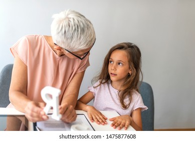 Proper Articulation Therapy For Girl. Stuttering Girl And Speech Therapist. Senior Female Speech Therapist Helping A Young Patient. Repeat After Me.. Session With Alphabet Learning