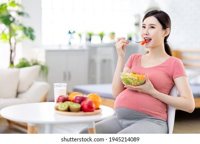 Proper Nutrition Concept - Asian Pregnant Woman With A Fork Eating Salad