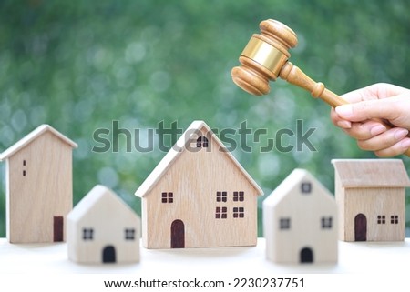 Property auction, Woman hand holding gavel wooden and model house on natural green background, lawyer of home real estate and ownership property concept 