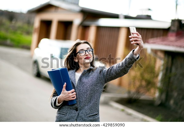 Property businesswoman, bank and insurance worker
people concept - beautiful successfull woman in sunglasses make
photo on camera while walking outdoor. City business woman working.
Stylish purse.