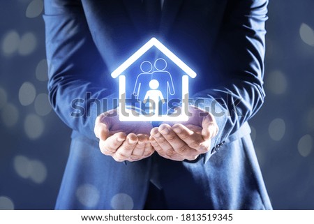 Property insurance concept. Man demonstrating house with family image, closeup