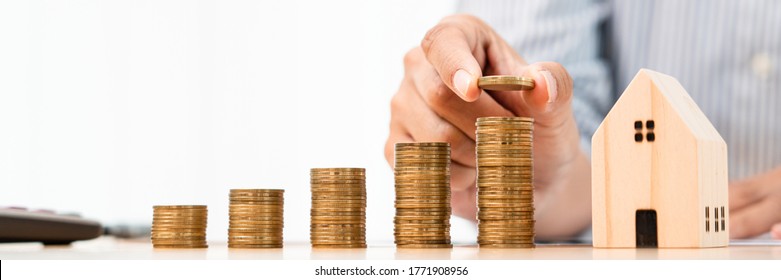 Property investment and house mortgage financial concept, hand of a businessman who is stacking coins for Real estate investment, saving for buying for housing or speculation - Shutterstock ID 1771908956
