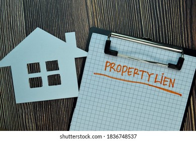 Property Lien Write On A Paperwork Isolated On Wooden Table. Business Or Financial Concept