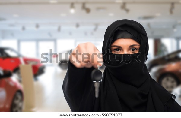 property and people concept - muslim\
woman in hijab with car key over car show\
background