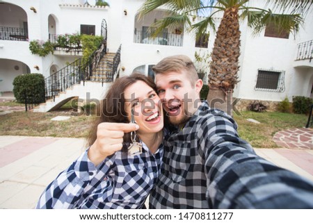 Property, real estate and apartment concept - Happy funny young couple showing a keys of their new house