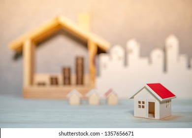 Property or real estate investment concept. Home mortgage loan rate. Saving money for future retirement. Miniature house model with blurred stacked coins and city background on wooden table. - Shutterstock ID 1357656671