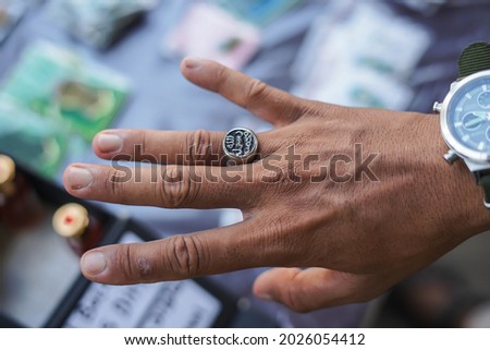 The prophet muhammad ring was silver and black. It's in the hands of a Muslim man with the blur's background.