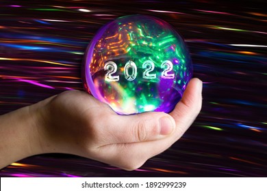 Prophetic glowing sphere in the palm with the inscription 2022. Discover the future.What will the year 2022 bring us? Happy New Year.