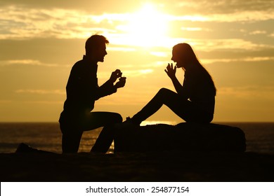 Proposal on the beach with a man silhouette asking for marry at sunset with the sun in the background