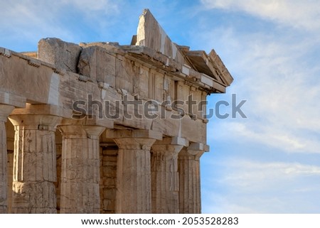 The Propylaea was the monumental gateway to the Acropolis of Athens. Detail of the frieze, cornice and the doric order capitals of the columns at the back side of the building. Sunny day, clouds