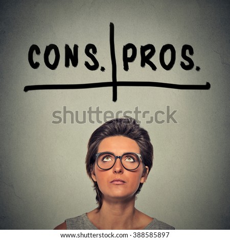 pros and cons, for and against argument concept. Young business woman with glasses looking up deciding isolated on gray wall background. Face expression, emotion, feeling, perception, vision, decision