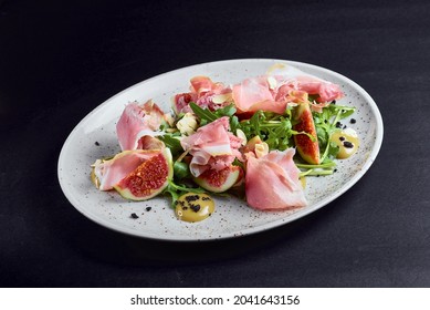 Prosciutto with fresh figs salad served on a white plate with black background. Healthy eating concept. - Powered by Shutterstock